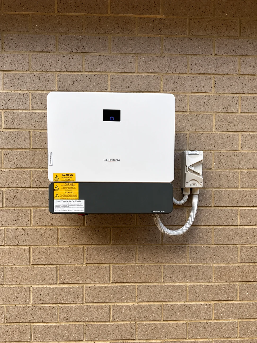 Wall-mounted solar inverter and electrical isolators on an exterior brick wall