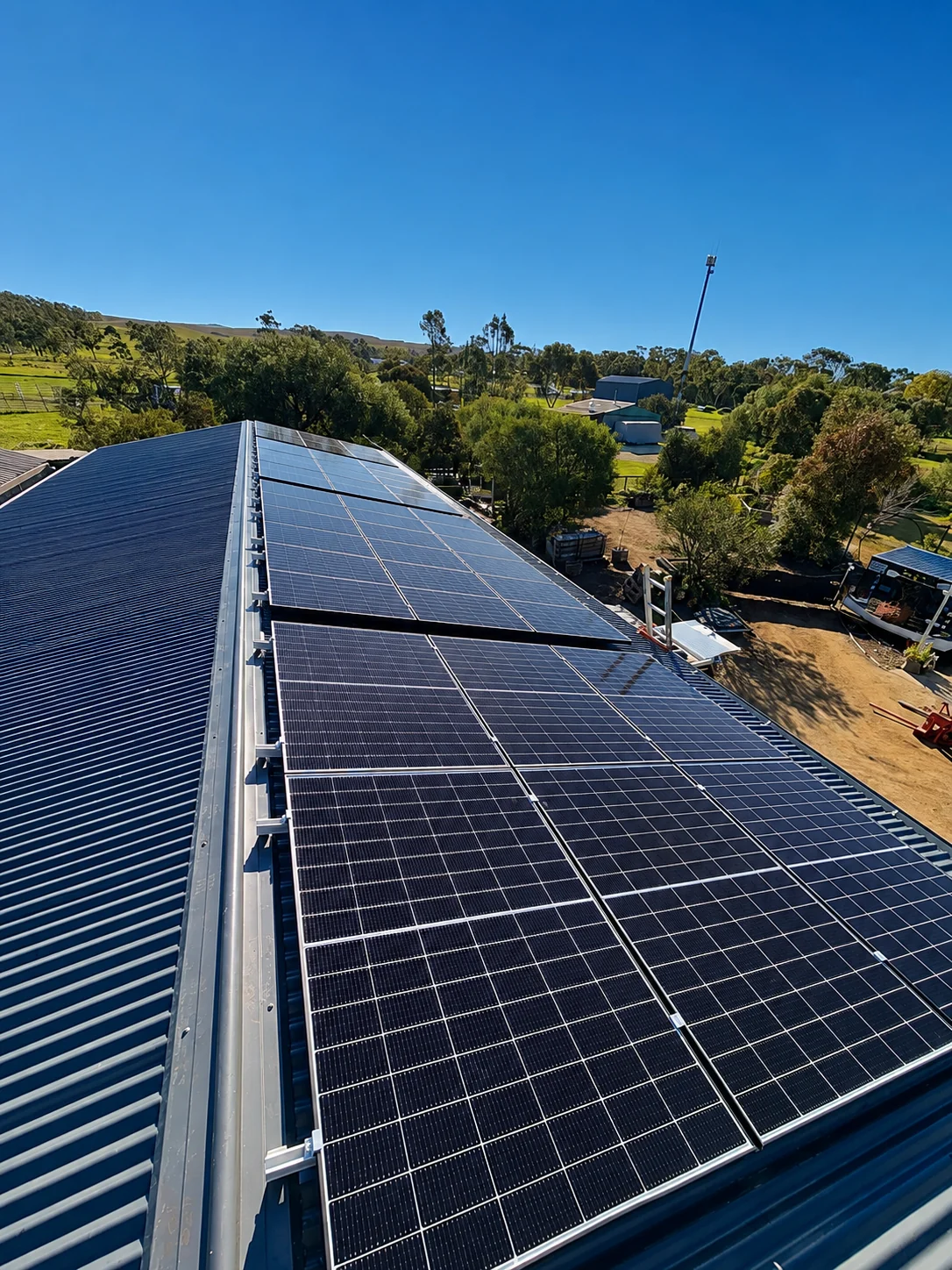 Solar panels installed on a corrugated metal roof overlooking a rural landscape